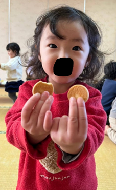 食べかけのビスケットとかじっていないビスケットを差し出す子供